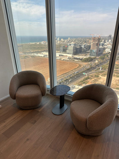 שולחן צד אמבר משיש טבעי חום בין שתי כורסאות מול החלון
